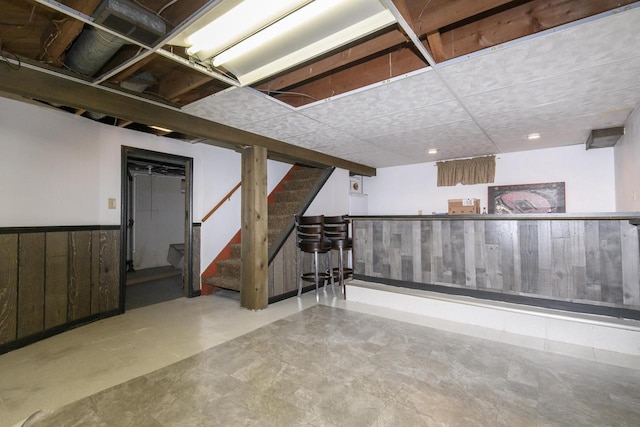 finished basement featuring wainscoting and stairs