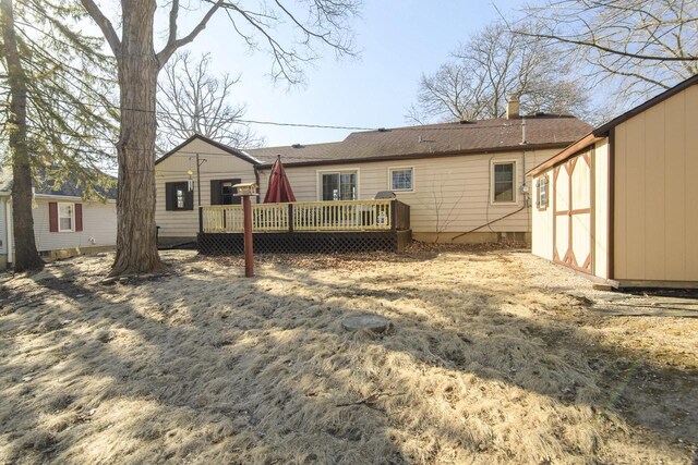 rear view of property with an outbuilding, a chimney, and a deck