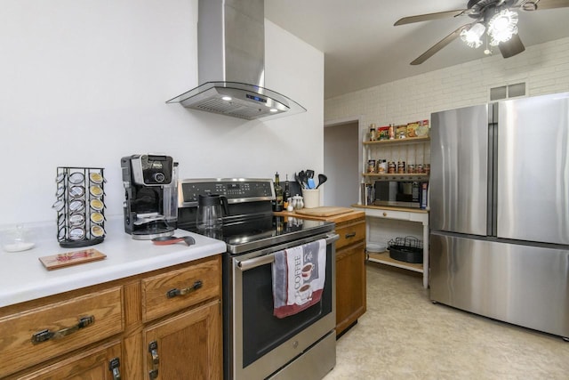 kitchen with light countertops, appliances with stainless steel finishes, brown cabinetry, and wall chimney range hood