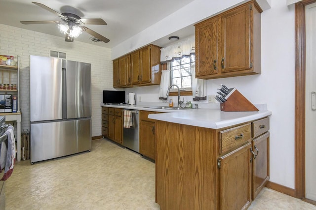 kitchen with ceiling fan, light countertops, brown cabinets, appliances with stainless steel finishes, and a sink