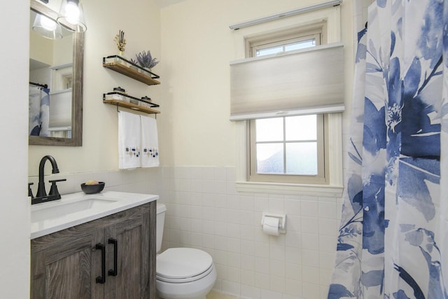 bathroom featuring a wainscoted wall, toilet, curtained shower, tile walls, and vanity