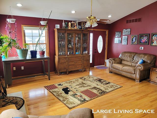 living area with visible vents, lofted ceiling, ceiling fan, wood finished floors, and recessed lighting