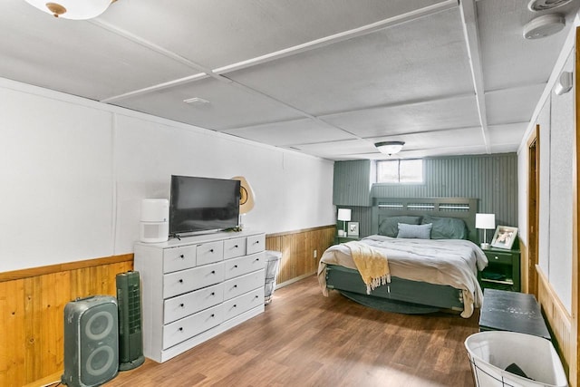 bedroom featuring a wainscoted wall, wood finished floors, and wood walls