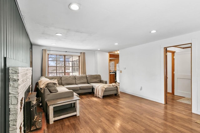 living area with baseboards, recessed lighting, a fireplace, and light wood-style floors