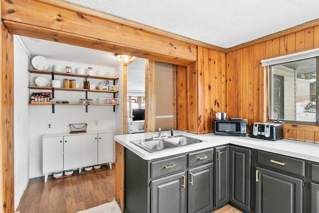 kitchen with black microwave, light countertops, a sink, and gray cabinetry