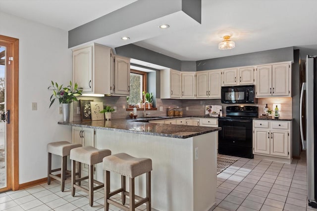 kitchen with a peninsula, black appliances, and light tile patterned flooring