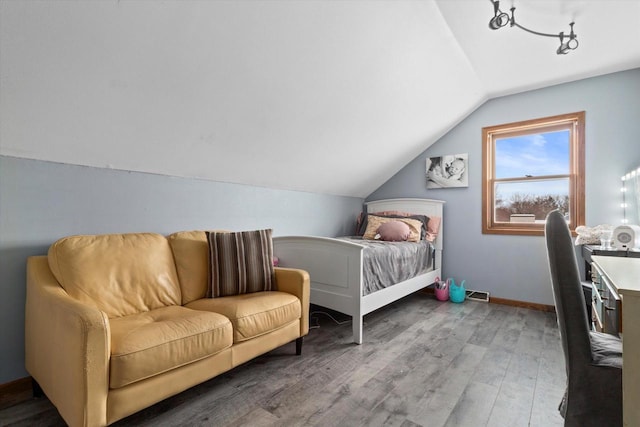 bedroom with vaulted ceiling, wood finished floors, and baseboards