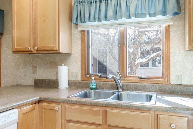 kitchen featuring light brown cabinets, white dishwasher, light countertops, and a sink