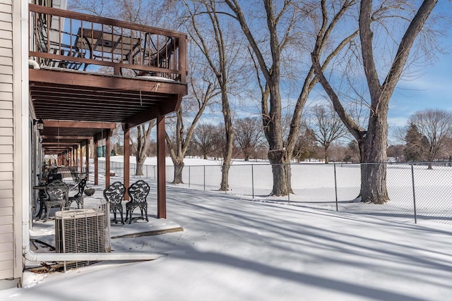 yard covered in snow with fence, a deck, and cooling unit