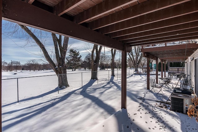 snowy yard featuring central AC and fence