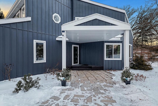 snow covered rear of property featuring board and batten siding