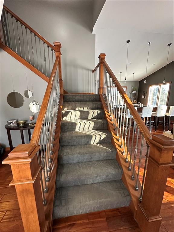 staircase with vaulted ceiling and wood finished floors