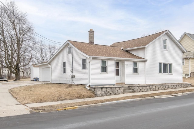 view of front of house featuring a garage, roof with shingles, and a chimney