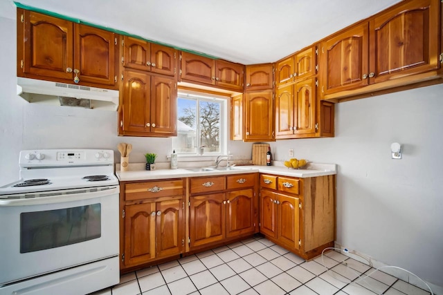 kitchen featuring electric range, brown cabinetry, light countertops, under cabinet range hood, and a sink