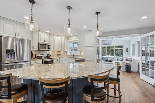 kitchen with light stone counters, decorative backsplash, light wood-style floors, white cabinets, and stainless steel appliances