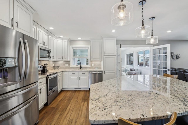 kitchen with a sink, dark wood-type flooring, white cabinets, appliances with stainless steel finishes, and backsplash