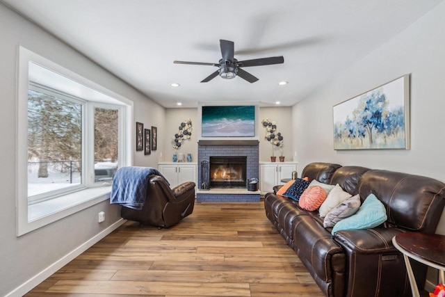 living area with a brick fireplace, recessed lighting, wood finished floors, and baseboards