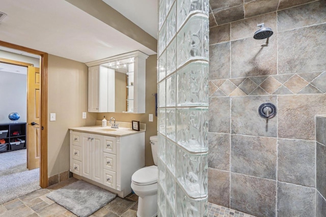 full bathroom featuring vanity, stone tile floors, toilet, and a walk in shower