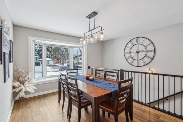 dining space with wood finished floors, baseboards, and a chandelier