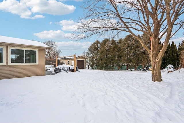 snowy yard with a detached garage and an outdoor structure