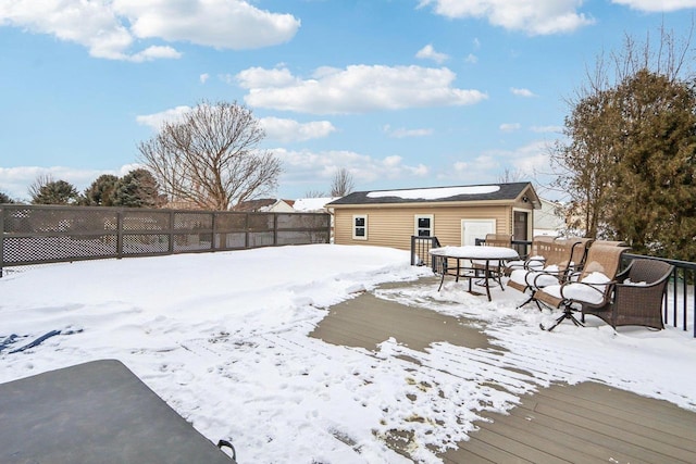 snowy yard featuring outdoor dining space, a wooden deck, and a fenced backyard