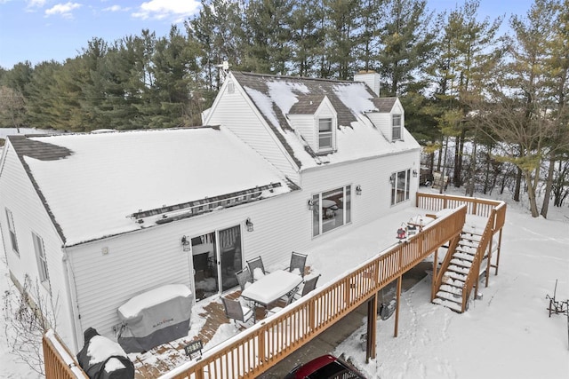 snow covered rear of property featuring stairs and a wooden deck