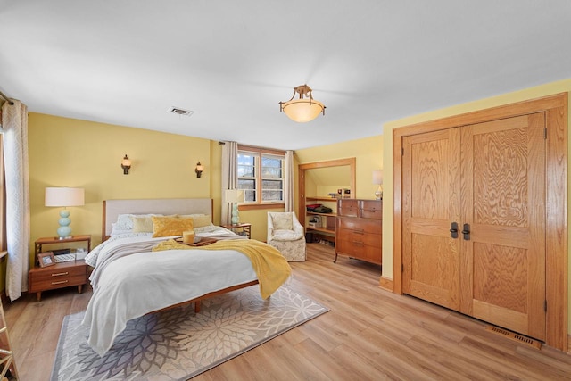 bedroom with light wood-style floors, a closet, visible vents, and vaulted ceiling