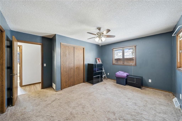 bedroom featuring a ceiling fan, a closet, light colored carpet, and baseboards