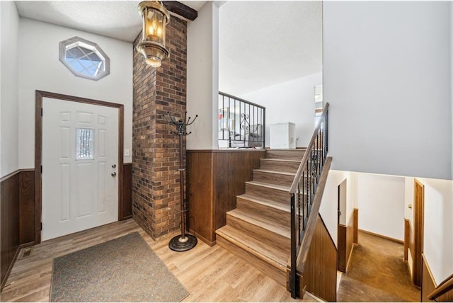 foyer entrance with a wainscoted wall, stairway, a wealth of natural light, and wood finished floors