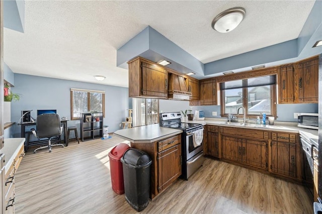 kitchen with brown cabinets, light wood-style floors, a sink, and stainless steel range with electric cooktop