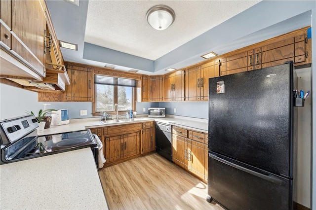 kitchen with brown cabinetry, light countertops, a sink, and black appliances