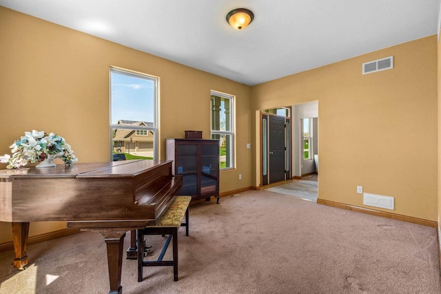 living area featuring visible vents, light carpet, and baseboards