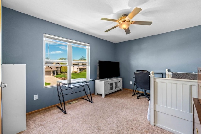 office space with a ceiling fan, light colored carpet, visible vents, and baseboards