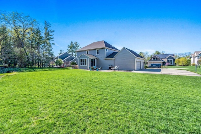 rear view of house with concrete driveway, a yard, and an attached garage