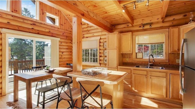 kitchen with beamed ceiling, a sink, freestanding refrigerator, rail lighting, and wood ceiling