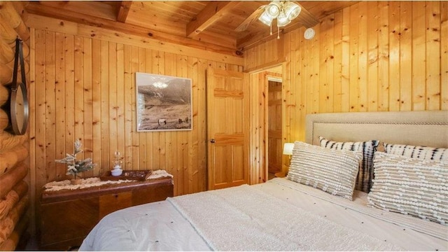 bedroom with beam ceiling, wood walls, and wooden ceiling