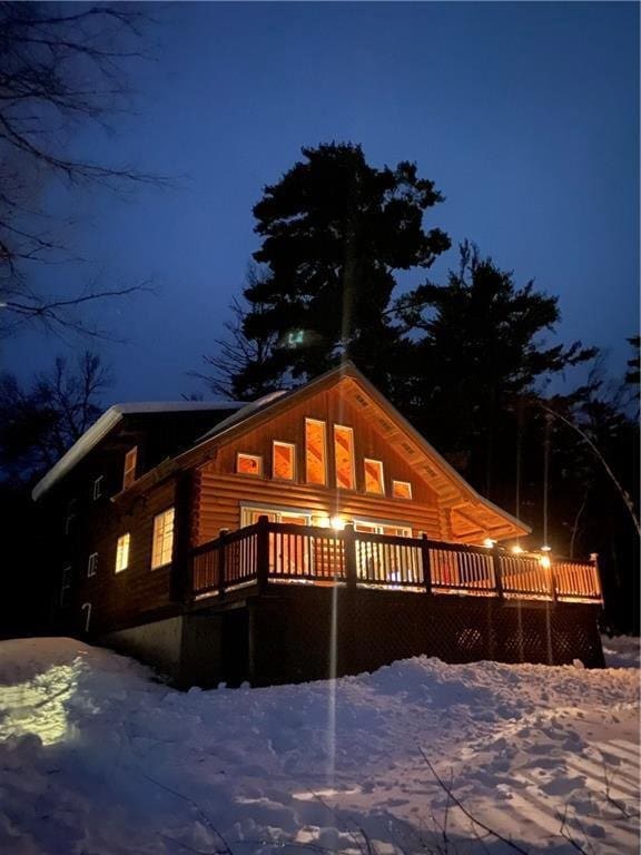 snow covered back of property with a deck