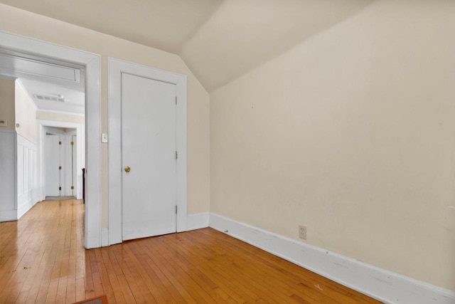 interior space with lofted ceiling, baseboards, visible vents, and wood finished floors