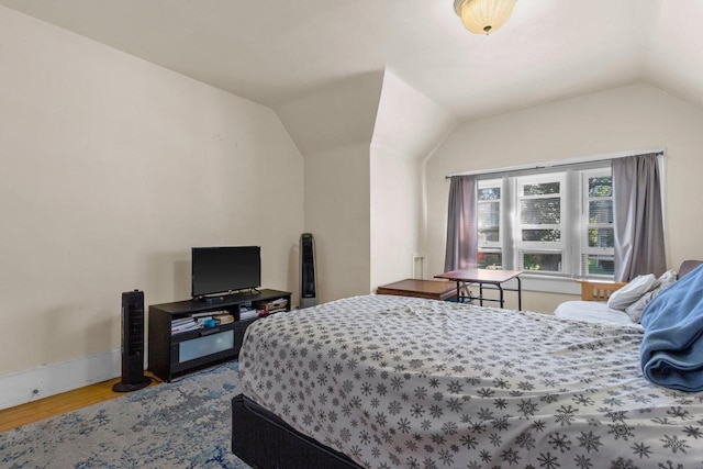 bedroom with vaulted ceiling, light wood finished floors, and baseboards