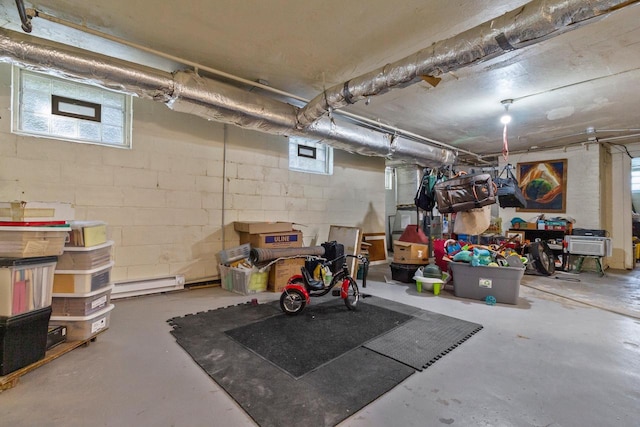 basement with a baseboard heating unit and concrete block wall