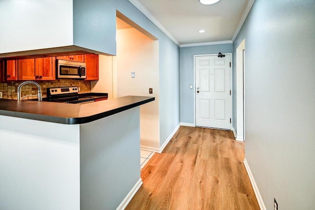 hallway featuring recessed lighting, a sink, baseboards, ornamental molding, and light wood finished floors