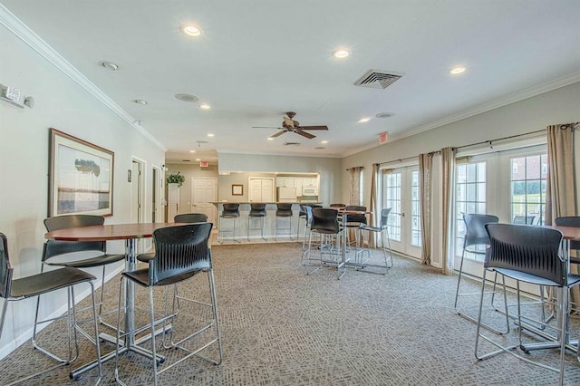 dining room featuring french doors, light colored carpet, visible vents, and crown molding