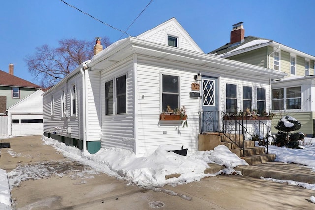 view of front of house with a garage, a chimney, and an outdoor structure