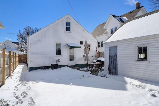 snow covered house featuring fence