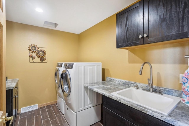 washroom featuring a sink, visible vents, independent washer and dryer, cabinet space, and wood tiled floor