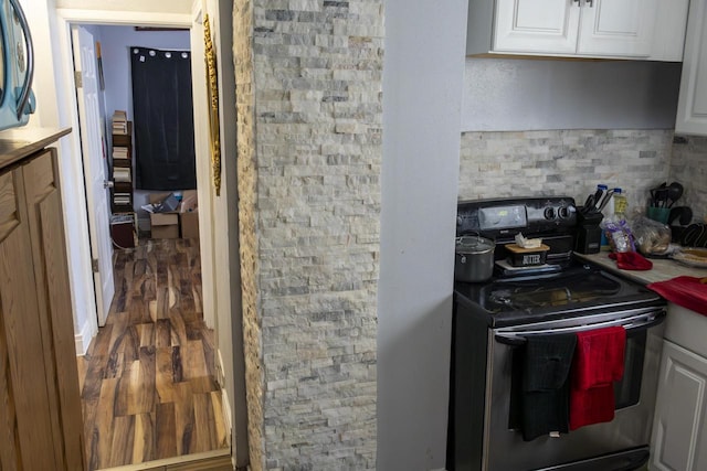 kitchen featuring dark wood-style floors, electric stove, white cabinetry, and backsplash