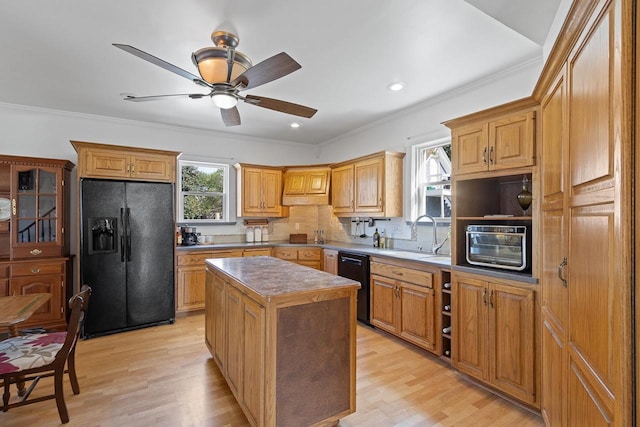 kitchen featuring a center island, crown molding, light wood finished floors, a sink, and black appliances