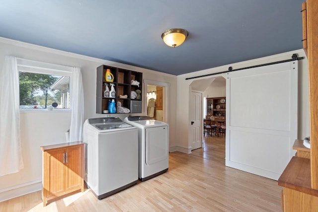 clothes washing area featuring laundry area, light wood finished floors, a barn door, arched walkways, and washing machine and dryer