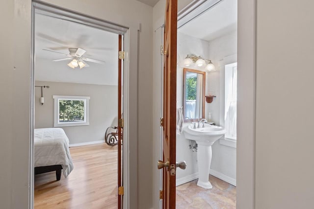 ensuite bathroom featuring a sink, baseboards, a ceiling fan, and ensuite bathroom