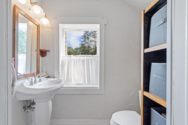 bathroom with baseboards, a textured wall, and toilet